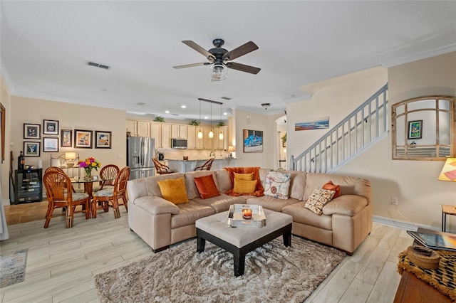 living room with light hardwood / wood-style flooring, ceiling fan, and ornamental molding