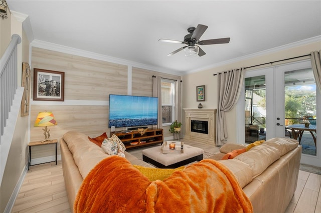 living room with wood walls, french doors, ceiling fan, ornamental molding, and light hardwood / wood-style floors