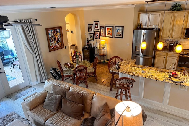 kitchen featuring light stone countertops, light wood-type flooring, ornamental molding, stainless steel appliances, and decorative light fixtures