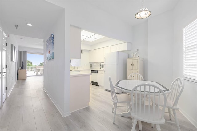 kitchen with pendant lighting, sink, white cabinetry, light hardwood / wood-style flooring, and white appliances