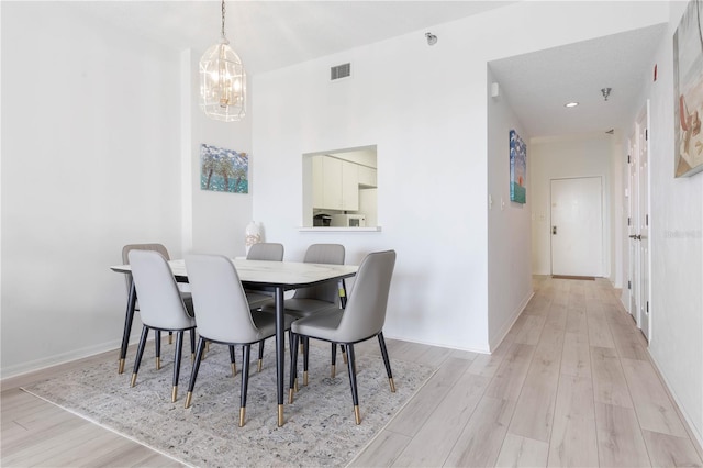 dining room featuring light wood-type flooring and a notable chandelier