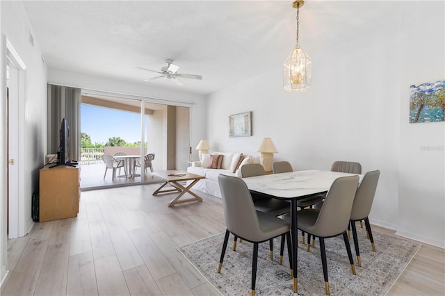 dining area featuring light wood-type flooring and ceiling fan with notable chandelier