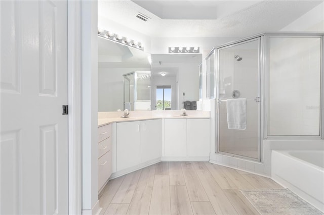 bathroom with independent shower and bath, wood-type flooring, vanity, and a textured ceiling