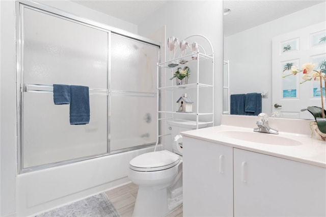 full bathroom featuring enclosed tub / shower combo, vanity, toilet, and a textured ceiling