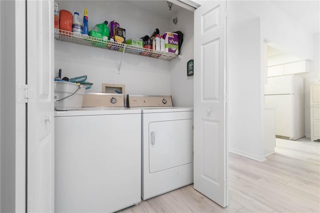 clothes washing area with light hardwood / wood-style floors and washer and dryer