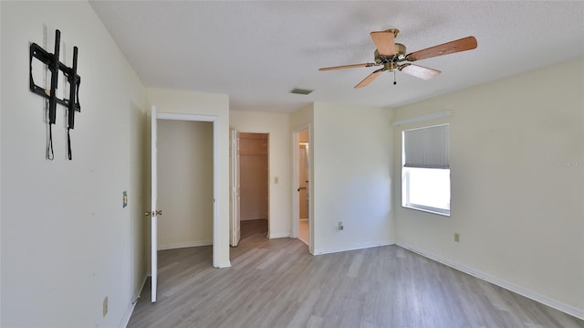 unfurnished bedroom featuring baseboards, visible vents, a textured ceiling, and light wood finished floors