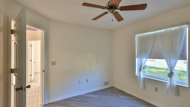 unfurnished room with baseboards, visible vents, ceiling fan, wood finished floors, and a textured ceiling