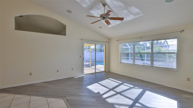 empty room with ceiling fan, a textured ceiling, vaulted ceiling, and wood finished floors