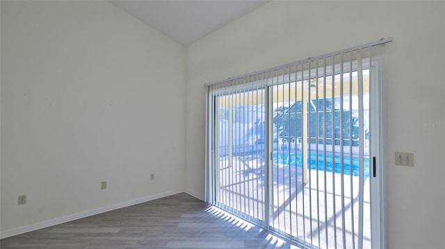 unfurnished room with vaulted ceiling, baseboards, and wood finished floors