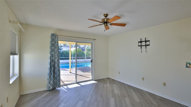 spare room with a textured ceiling, wood finished floors, a ceiling fan, and baseboards