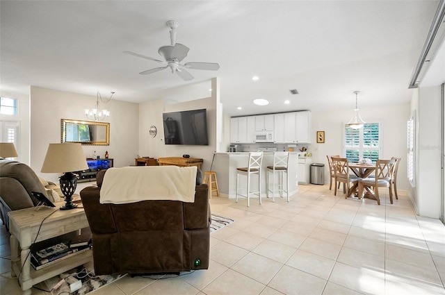 living room with ceiling fan with notable chandelier and light tile patterned floors