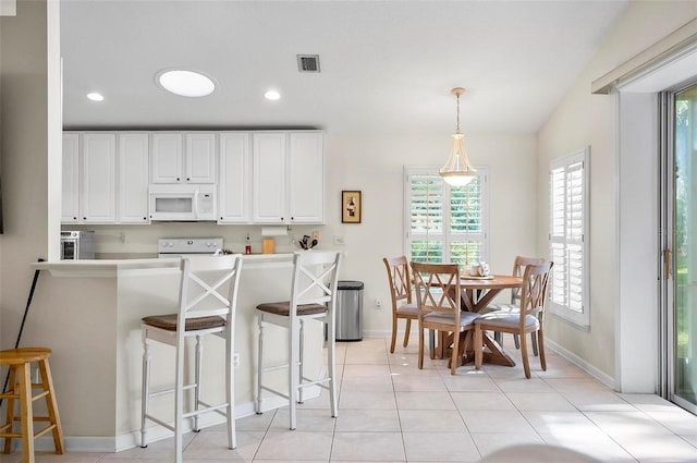 kitchen featuring range, white cabinetry, lofted ceiling, pendant lighting, and a breakfast bar area