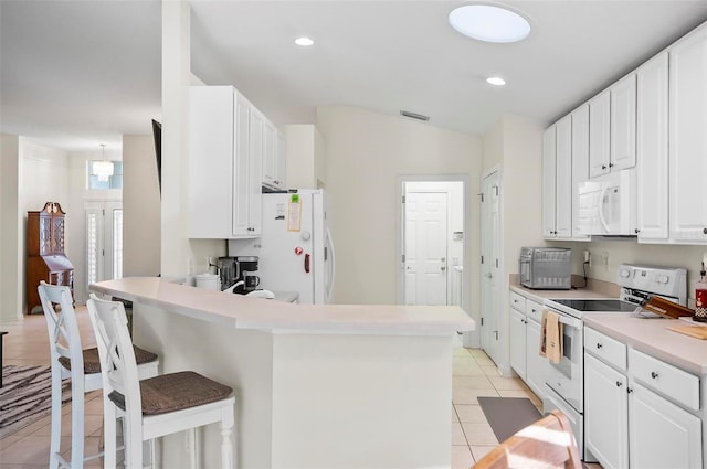 32 Shinnecock Dr, Palm Coast, FL 32137 - kitchen with white appliances, a kitchen bar, light tile patterned flooring, white cabinetry, and light countertops