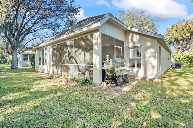 32 Shinnecock Dr, Palm Coast, FL 32137 - view of side of home featuring a sunroom, cooling unit, a yard, and stucco siding