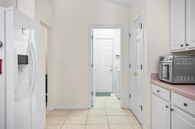 kitchen with lofted ceiling, white cabinets, white refrigerator with ice dispenser, and light tile patterned flooring