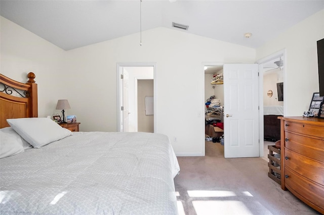 bedroom with a closet, light carpet, a spacious closet, vaulted ceiling, and ensuite bathroom