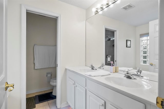 bathroom with toilet, a textured ceiling, vanity, and tile patterned flooring