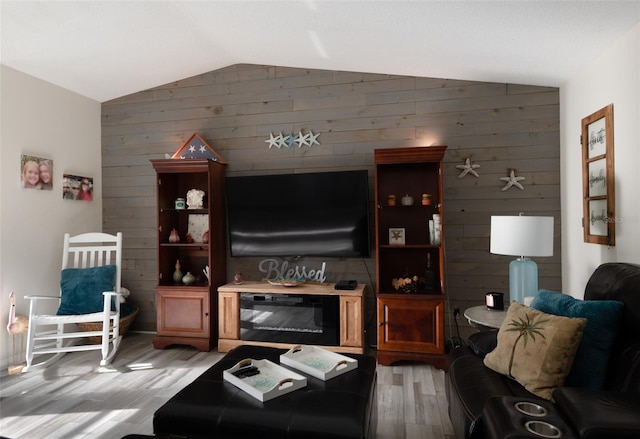 living room featuring light wood-type flooring, lofted ceiling, and wooden walls