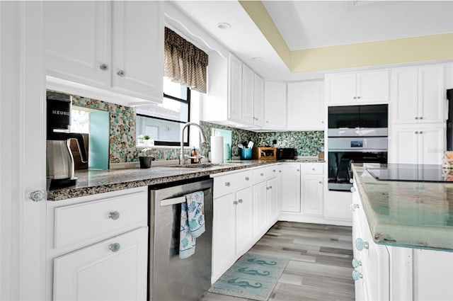 kitchen with black electric cooktop, dishwasher, sink, backsplash, and white cabinetry