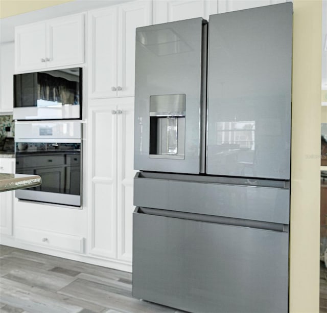 kitchen with white cabinets, appliances with stainless steel finishes, and wood-type flooring