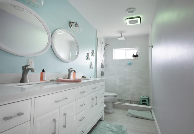 bathroom with tiled shower, vanity, and toilet