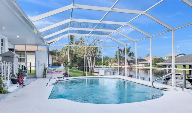 view of pool with glass enclosure, a water view, and a patio area