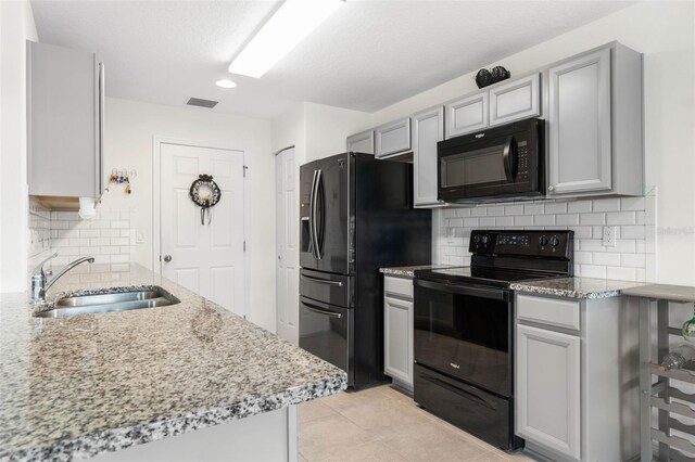 38 Colechester Ln, Palm Coast, FL 32137 - kitchen featuring black appliances, a sink, gray cabinetry, backsplash, and light stone counters