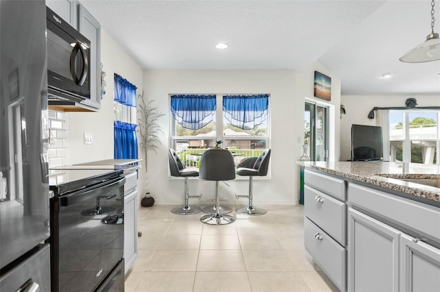 kitchen featuring gray cabinets, a healthy amount of sunlight, light tile patterned floors, and black appliances