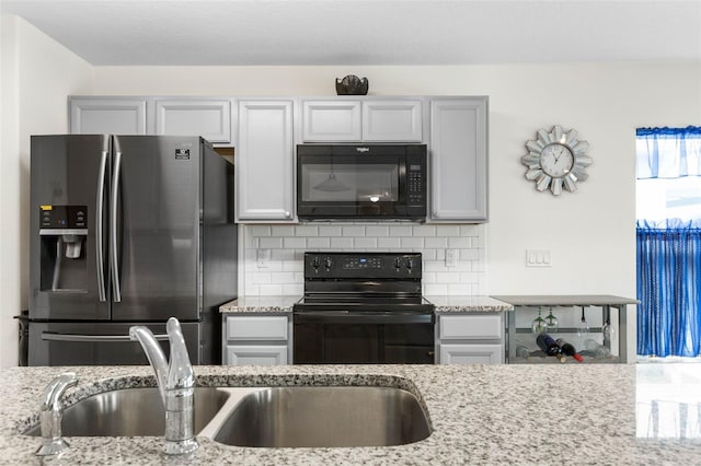 38 Colechester Ln, Palm Coast, FL 32137 - kitchen with black appliances, decorative backsplash, light stone countertops, and a sink