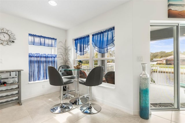 dining area featuring plenty of natural light, a water view, and tile patterned floors