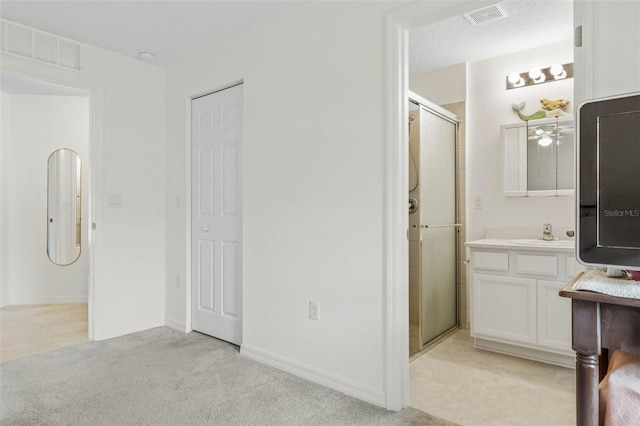 bathroom featuring walk in shower, vanity, a textured ceiling, and tile patterned floors