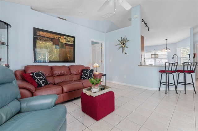 living room with vaulted ceiling, light tile patterned flooring, and ceiling fan with notable chandelier