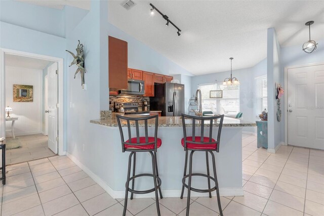 kitchen with a chandelier, kitchen peninsula, appliances with stainless steel finishes, and a kitchen breakfast bar