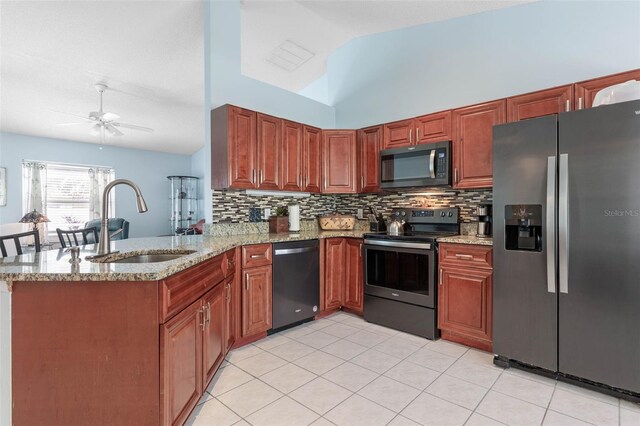 kitchen featuring stainless steel appliances, sink, kitchen peninsula, light stone countertops, and ceiling fan