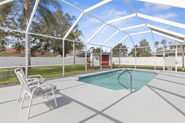 view of pool with glass enclosure, a yard, a patio, and a storage shed