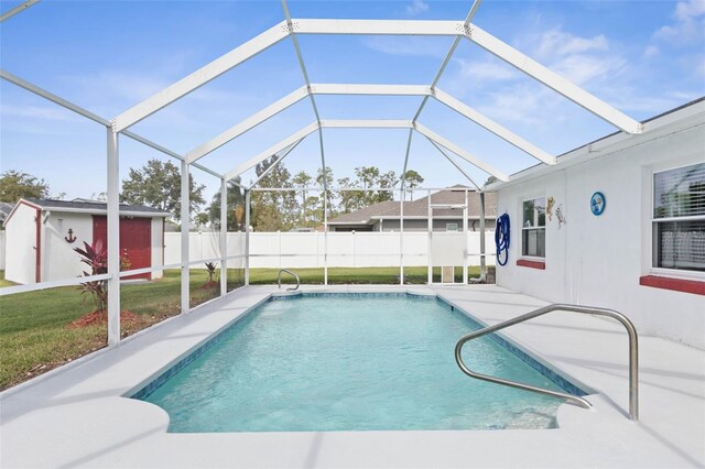 view of pool featuring glass enclosure, a yard, a patio, and an outdoor structure