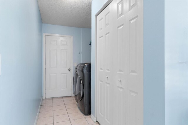 laundry area with a textured ceiling, washer and clothes dryer, and light tile patterned floors