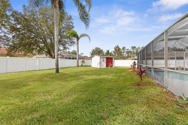 view of yard with a fenced in pool, glass enclosure, and a storage unit