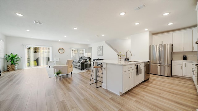 kitchen featuring white cabinets, a center island with sink, sink, and appliances with stainless steel finishes