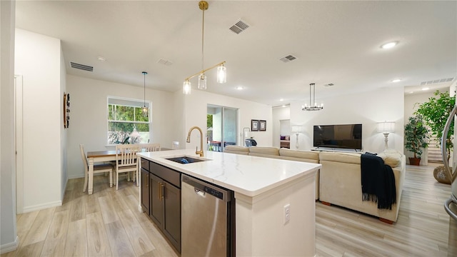 kitchen with a center island with sink, dishwasher, sink, light stone countertops, and light hardwood / wood-style flooring