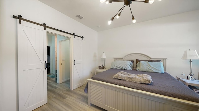 bedroom with a barn door and light hardwood / wood-style floors