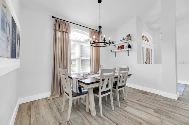 dining area with light hardwood / wood-style floors and a notable chandelier