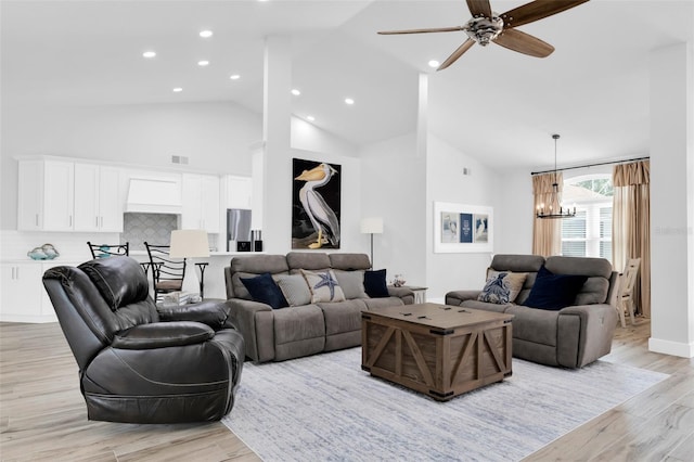 living room with high vaulted ceiling, light hardwood / wood-style floors, and ceiling fan with notable chandelier