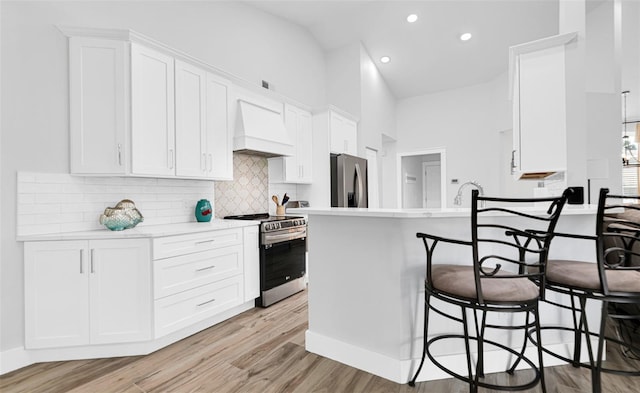 kitchen featuring light hardwood / wood-style flooring, white cabinets, premium range hood, and stainless steel appliances