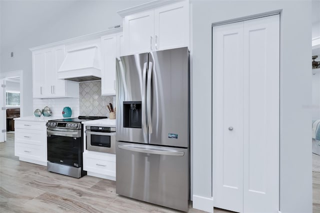 kitchen with white cabinets, decorative backsplash, custom exhaust hood, and appliances with stainless steel finishes