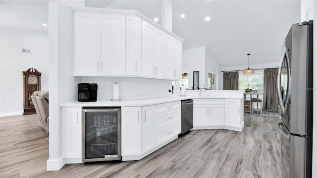 kitchen with stainless steel appliances, beverage cooler, a peninsula, high vaulted ceiling, and white cabinetry