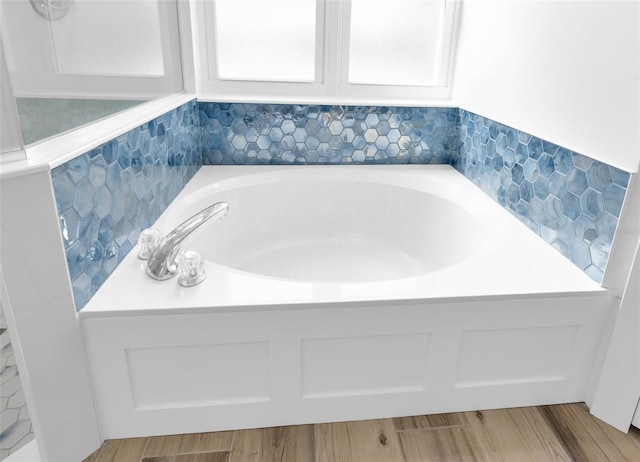 bathroom featuring hardwood / wood-style floors, a tub to relax in, and tile walls