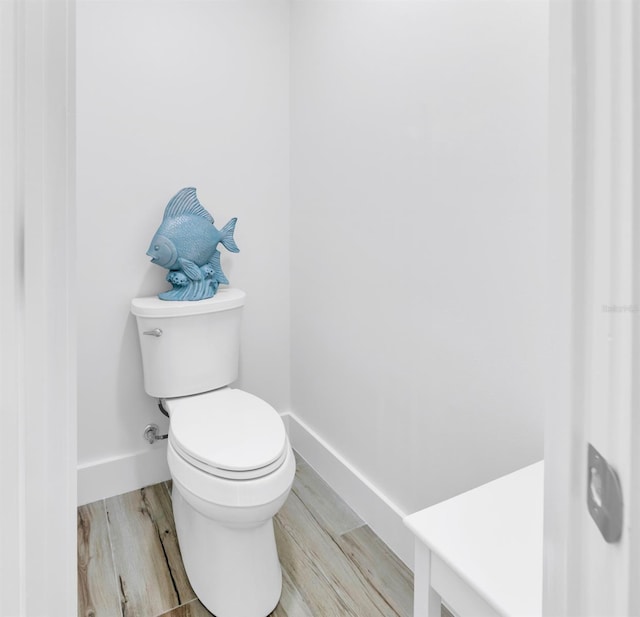 bathroom featuring baseboards, toilet, and wood finished floors