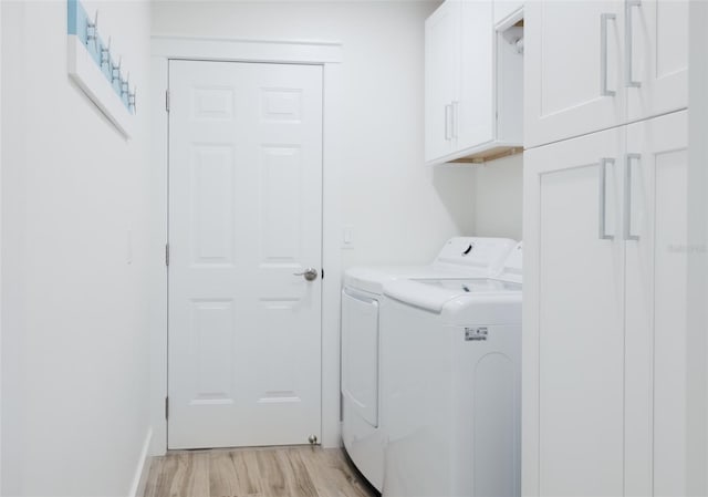 clothes washing area featuring cabinets, light hardwood / wood-style floors, and washing machine and clothes dryer