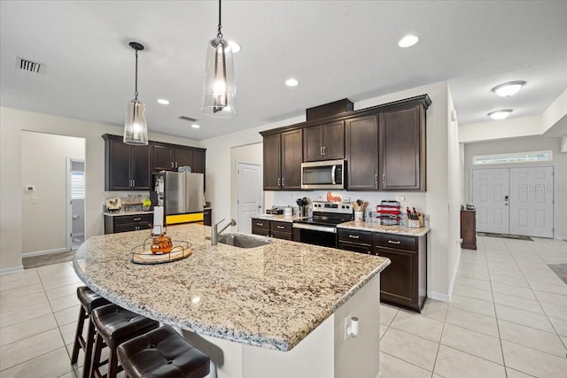 kitchen with hanging light fixtures, stainless steel appliances, and a kitchen island with sink